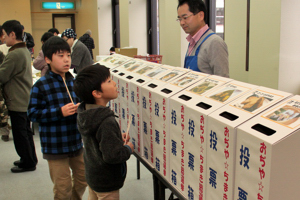 投票箱の前で悩む子どもたちの画像