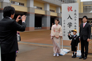 入学式の看板の前で記念撮影する家族の画像