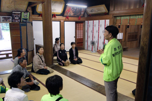 魚沼神社内で説明に聴き入る参加者の画像