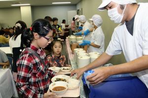 給食を配膳してもらう来場者の画像