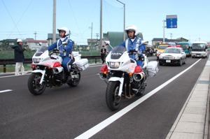 開通した道路を走る白バイなどの画像