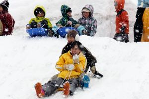 雪のすべり台をすべる子どもたちの画像