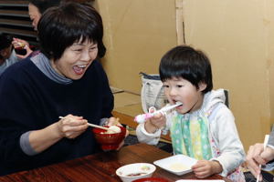 餅を食べる家族連れの画像