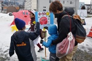 雪像コンテストに投票する親子の画像