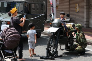 自衛隊のバイクに乗り記念撮影をする子どもの画像