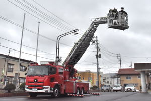 はしご車の上から手を振る二人の画像