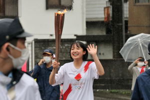 トーチを持ち沿道に手を振る西脇さんの画像