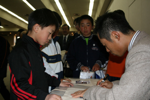 サインする井佐選手と子どもたちの画像