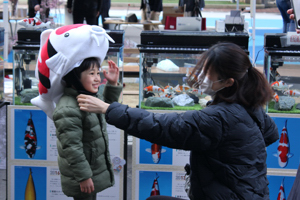 錦鯉キャップをかぶって写真を撮る子どもの画像