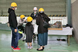 自転車をこいで発電する男の子とそれを見守る家族の画像