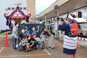 神輿の前で写真を撮る親子の画像