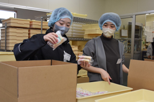 お菓子の箱詰め作業を行う学生のみなさんの画像