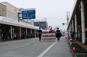 分列行進をする消防団とそれを見守る市民の画像