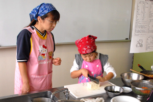 材料を切る子どもと心配そうに見守る保護者の様子の画像