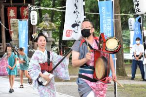 三味線を演奏しながら境内を練り歩く男性と女性の画像