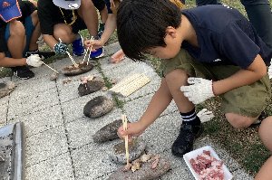 河原で拾った石で肉を焼く参加者の画像