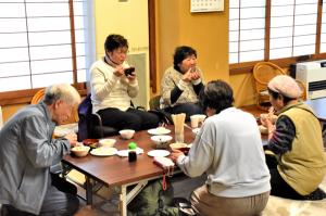 試食会でつきたての餅を食べる人の画像