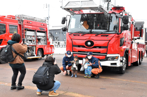 消防車の前で消防士と記念撮影をする子どもたちの画像