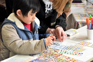 タイムカプセルチェキにメッセージを書く子どもの画像