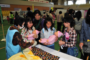 助産師会コーナーで赤ん坊の人形を抱く子どもの画像