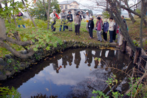 縮をさらしたといわれている「お満ヶ池」を見学する参加者の画像