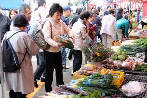 野菜を買い求めるお客さんの画像