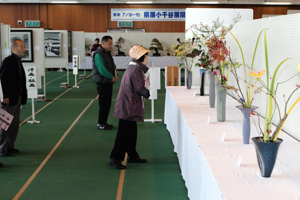 展示された生け花を見る来場者の画像