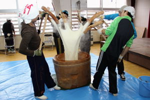 杵を持ち上げ、餅の花を咲かす保存会のみなさんの画像