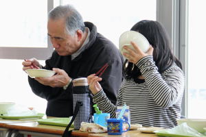 一緒に給食を食べる小学生と富久寿大学の方の画像