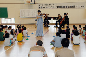 児童の間を歩きながら演奏するヴァイオリニストの画像