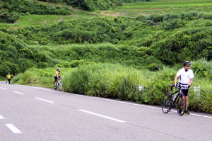 自転車を押して山道を登る選手の画像