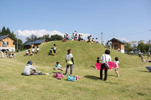 広場で遊ぶ家族連れの画像