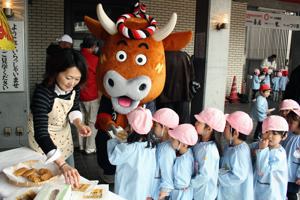 焼きあがったよし太くん焼きを幼稚園児に配るよし太くんの画像