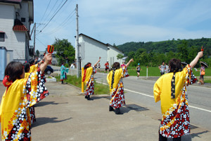 よさこいを踊りながら応援する地域の方々の画像