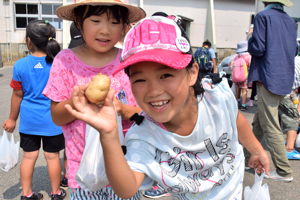 お土産のじゃがいもを手にする女の子の画像