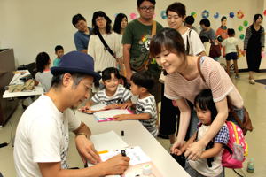 絵本にサインをする鈴木さんと子どもたちの画像