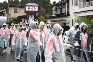 雨の中、雨合羽を着て屋台を引く42歳同級会のみなさんの画像