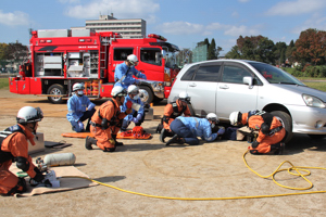 車の下敷きになった人を救出している画像