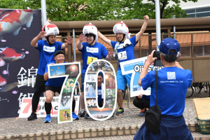 市制施行70周年記念パネルと記念撮影をする選手の画像