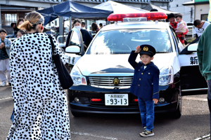 警察官の制服を着てパトカーの前で記念撮影する男の子の画像