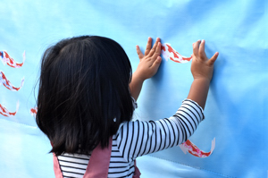 小千谷市の魅力を記入した錦鯉シールをモニュメントに貼る女の子の画像